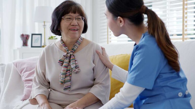 A family member reviews a care plan with an older resident at a table in an assisted living room.